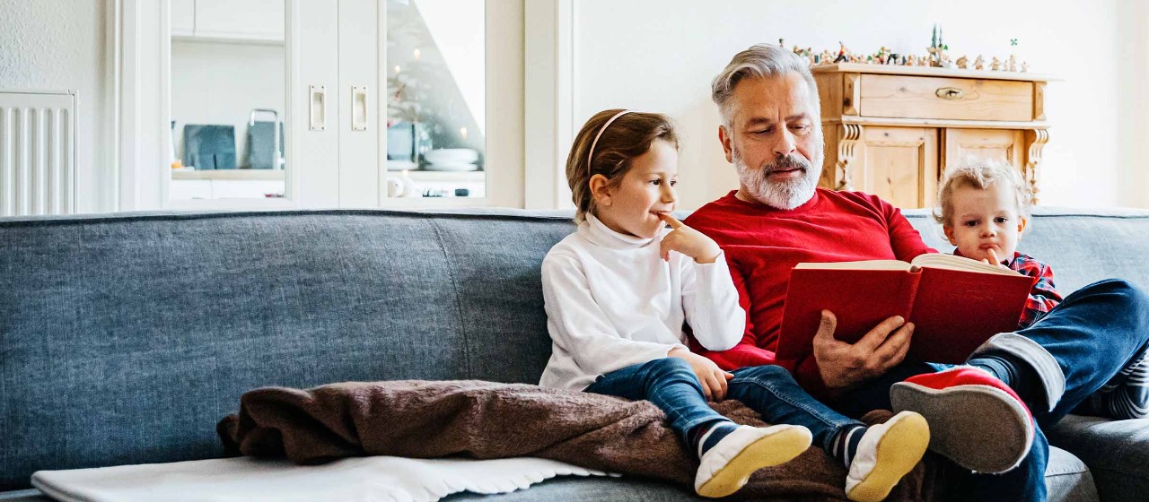 Mann sitzt mit Kindern auf dem Sofa