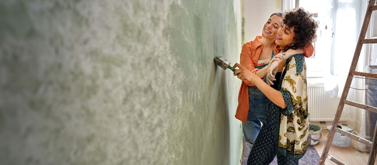 Zwei Frauen die Arm in Arm eine Wand streichen